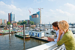 Couple looking to Elbe Philharmonic Hall construction site, HafenCity, Hamburg, Germany