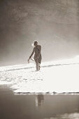 Junge Frau geht durchs flache Wasser am Strand, Fuerteventura, Spanien