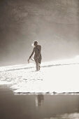 Young woman walking through shallow water at beach, Fuerteventura, Spain