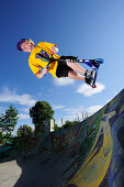 Junger Mann im Sprung mit einem Tretroller, Skatepark, München, Oberbayern, Bayern, Deutschland