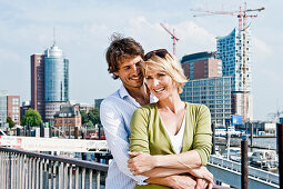 Couple embracing, Elbe Philharmonic Hall construction site in background, HafenCity, Hamburg, Germany