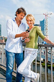 Couple with a smart phone, Elbe Philharmonic Hall construction site in background, HafenCity, Hamburg, Germany