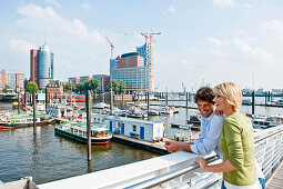 Young couple looking to the Elbphilharmonie at the harbour, Hamburg, Germany