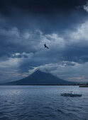 Man on zipline and fisherman with Mayon Volcano, Legazpi City, Luzon Island, Philippines, Asia