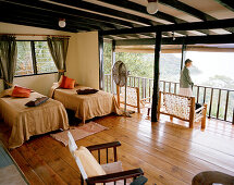 Woman on balcony of Superior Room Chalet, Mango Lodge, view over Anse Volbert, Bahia Ste. Anne, Praslin, Republic of Seychelles, Indian Ocean