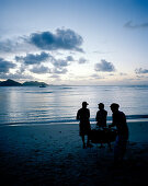 Creole fish barbecue on the beach in the evening, in the background neighbour island Praslin, La Digue, La Digue and Inner Islands, Republic of Seychelles, Indian Ocean