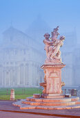 Fountain with statue in front of Santa Maria Assunta cathedral in the fog, Pisa, Tuscany, Italy, Europe