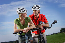 Cyclists leaning on handlebar, Lake Starnberg, Bavaria, Germany