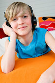 Boy lying on a bed, wearing headphones