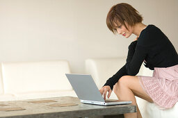 Young woman sitting on a sofa using laptop computer