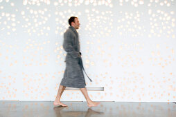 Man in grey bathrobe walking, side view
