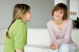 Smiling woman and little girl sitting in living-room