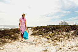 Young woman walking on the beach, rear view