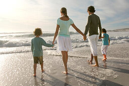Parents and two children walking on the beach, rear view, outdoors
