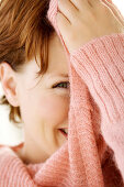 Portrait of young woman covering her face with jumper