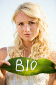 'Young woman holding a leaf with ''BIO'' lettering'