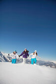 Three teenage girls in ski clothes, running in snow