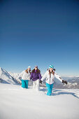 Three teenage girls in ski clothes, walking in snow