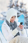 Young woman using mobile phone in snow