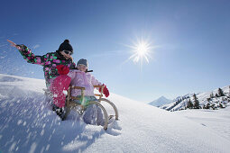 Two girls, 12 and 2 years, on a sledge, Kloesterle, Arlberg, Tyrol, Austria