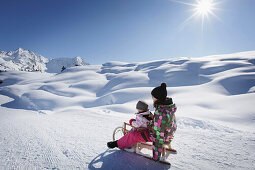 Two girls, 12 and 2 years, on a sledge, Kloesterle, Arlberg, Tyrol, Austria