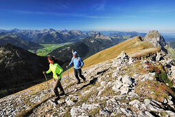 Couple walking at Brentenjoch with view to Tannheim valley and Tannheimer mountain range, Brentenjoch, Tannheimer mountain range, Allgaeu Alps, Tyrol, Austria