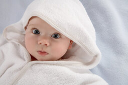 Baby wrapped in white hooded bathrobe