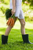 Young woman holding bunch of carrots