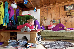 Drei junge Frauen entspannen nach dem Skifahren in einer gemütlichen Hütte, See, Tirol, Österreich