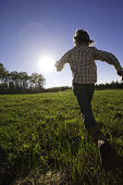 Young Girl in Jeans and Plaid Shirt  Running in Grass Field, Rear View, Oak Creek, Colorado, USA