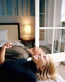 Couple lying on a double bed in a hotel room, spa resort, Travemuende, Luebeck, Schleswig-Holstein, Germany
