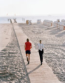Couple jogging at Baltic Sea beach, Travemuende, Luebeck, Schleswig-Holstein, Germany