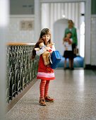 Girl with suitcase and rag doll in the hallway of a hotel, Rotterdam, Netherlands