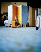 Girl reading on the floor inside a hotel room, Rotterdam, Netherlands