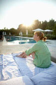 Frau sitzt auf einer Sonnenliege an einem Pool, Hotel La Réserve Ramatuelle, Chemin de la Quessine, Ramatuelle, Provence-Alpes-Côte d'Azur, Frankreich
