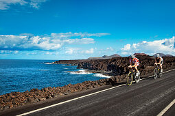 Cyclists at cliff coast, Los Hervideros, Lanzarote, Canary Islands, Spain, Europe