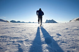 Mann läuft bei Sonnenaufgang über Gletscher, Blick zu Les Grandes Jorasses und Dent du Geant, Chamonix Mont Blanc, Frankreich, Europa