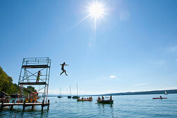 Kind springt von Sprungturm in Starnberger See, Oberbayern, Deutschland, Europa