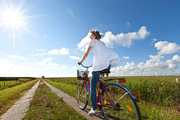 Young woman on bicycle in salt march, Wadden lands, North Sea coast, Lower Saxony, Germany, Europe