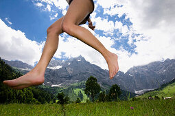 Junge Frau springt barfuß über Wiese, Eng, Ahornboden, Karwendel-Gebirge, Tirol, Österreich, Europa