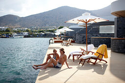 Couple sunbathing on the terrace of Yachting Club Villas, Elounda Beach Resort, Elounda, Crete, Greece