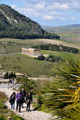 Four tourists with the view onto the Temple of Segesta in the background, Trapani, Sicily, Italy