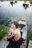 Boy sitting in a canoe, Klein Thurow, Roggendorf, Mecklenburg-Western Pomerania, Germany