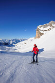 Woman with crosscountry skis ascending to Rofanspitze, Karwendel range in the background, Rofanspitze, Rofan, Tyrol, Austria, Europe