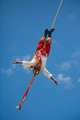 Ein junger Mann hängt an einem Seil von einem Pfahl während dem traditionellen Danza de los Voladores, Tanz der Flieger, Tulum, Riviera Maya, Quintana Roo, Mexiko, Mittelamerika