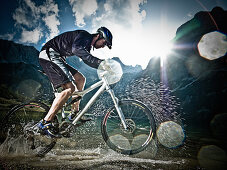 Male mountain biker riding through water