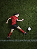 Soccer player laying on pitch. Soccer player kicking ball, lying on stadium grass