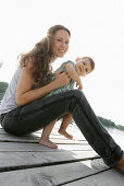 Young mother and daughter on wooden jetty, Old Danube, Vienna, Austria