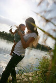 Young mother holding daughter at Danube riverbank, Old Danube, Vienna, Austria