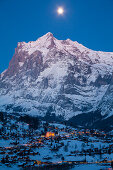 Abendstimmung und Vollmond über Grindelwald, dahinter das Wetterhorn, Wintersportort in der Jungfrauregion, Berner Oberland, Kanton Bern, Schweiz, Europa